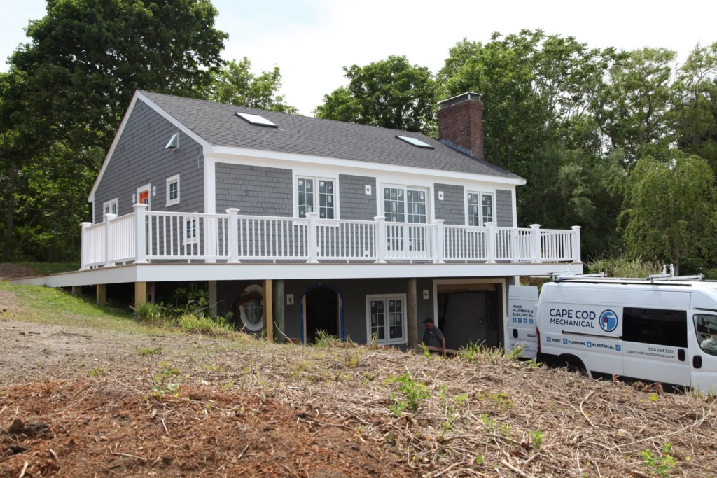 Gray Cape home with a white deck during renovation work in Dennis, MA