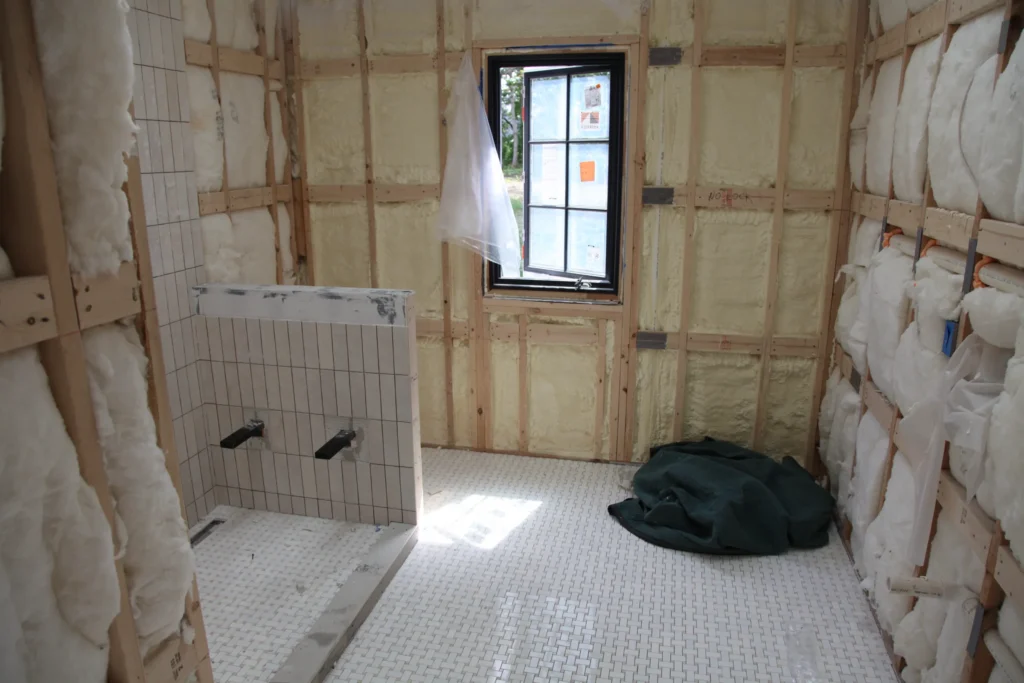 Bathroom with a tiled shower and exposed insulated walls during renovation in Dennis, MA
