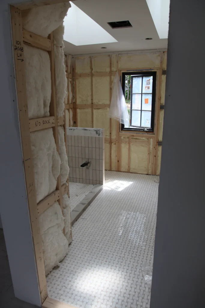 Bathroom renovation with skylights, tile floor, and exposed insulated walls in Dennis, MA