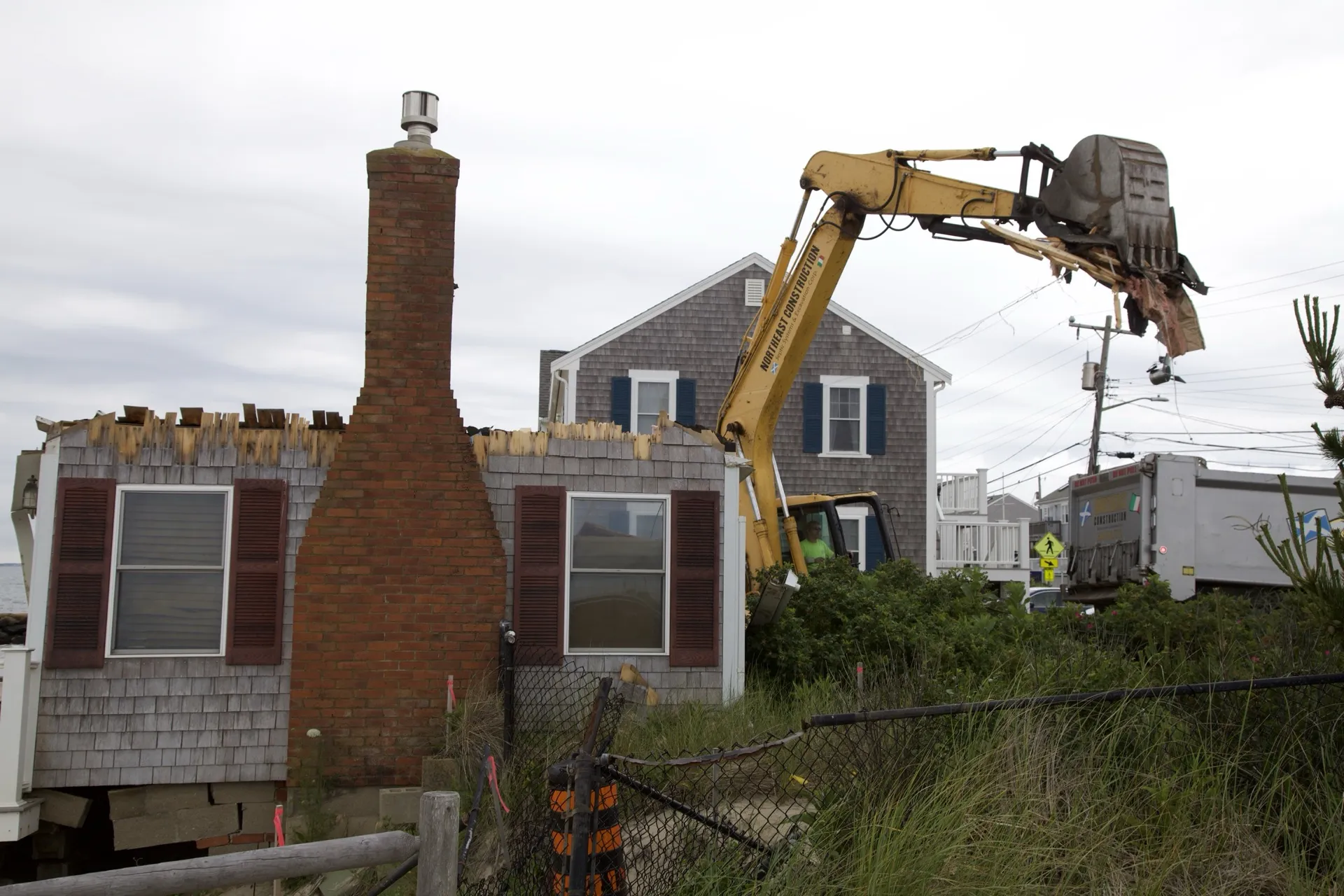 Excavator removing roof material; original brick chimney still standing on the Dennis Port lot.