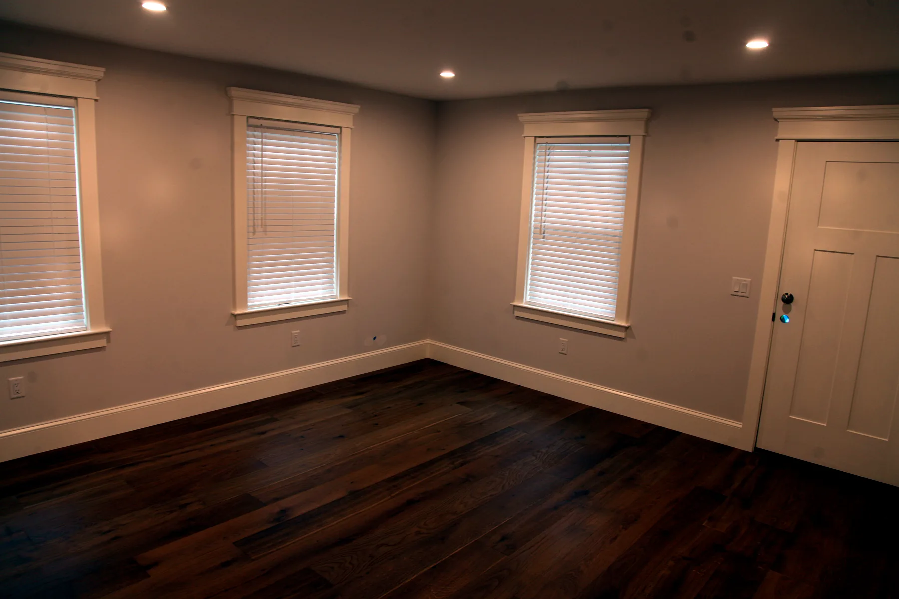 Finished room with hardwood floors, white trim, two windows, and recessed lighting